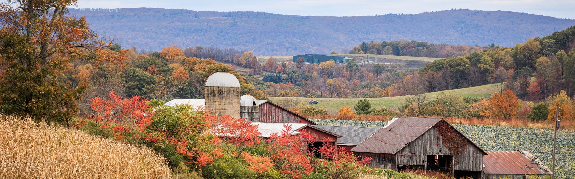 Rolling Pennsylvania farmland in autumn, with red barns, silos and wooded ridges in the distance.